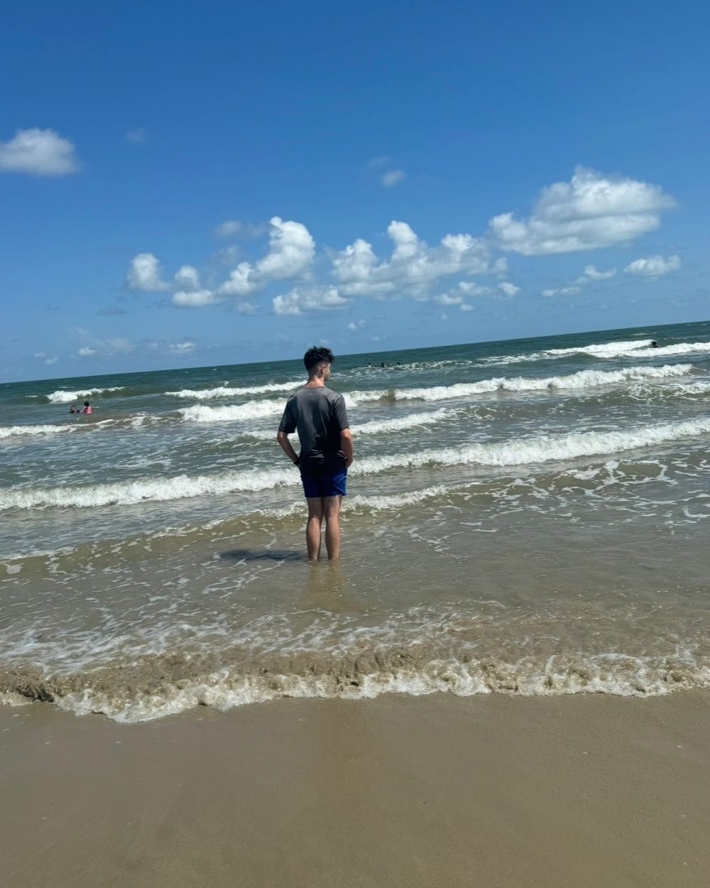 A young man, seen from behind, standing alone at the water&rsquo;s edge
